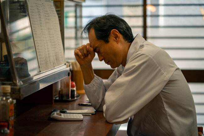 悩む飲食店の店主の画像